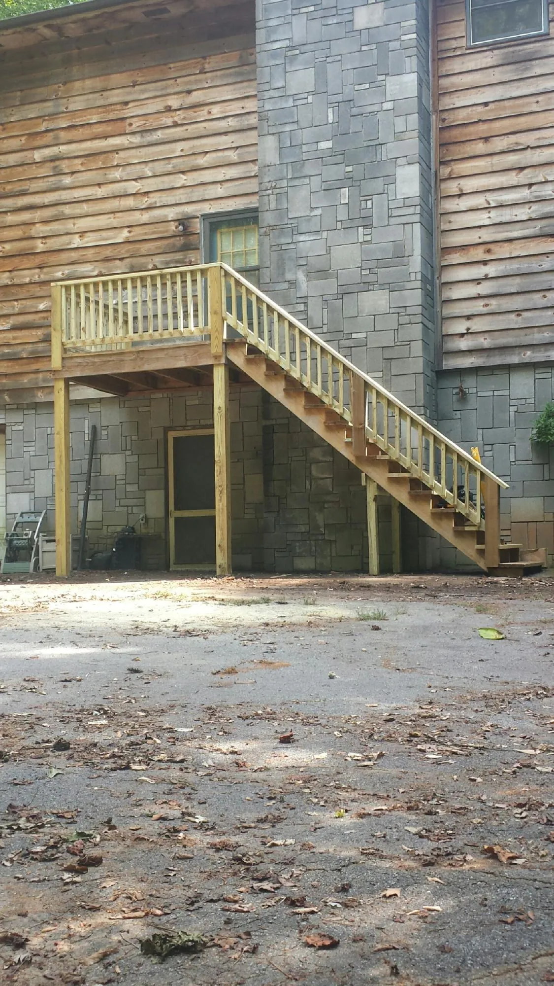 New pressure treated deck and stair landing on a log home in Shelby